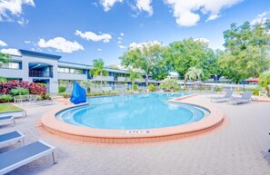 A swimming pool with a circular edge, surrounded by lounge chairs and a covered seating area. - Landing | Beautiful 1BD, Clubhouse, Gym (Kissimmee)