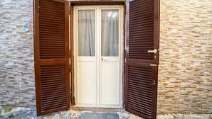 Une porte avec des volets en bois, encadrée dans un mur de pierre.