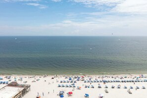 A beach with umbrellas and people. - Gulf front condo with community outdoor & indoor pool, hot tub & fitness center (Gulf Shores)