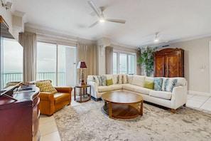 A living room with a sofa, coffee table, and a desk with a lamp. - Condo with great views, two pools, & private balcony - near attractions (Gulf Shores)