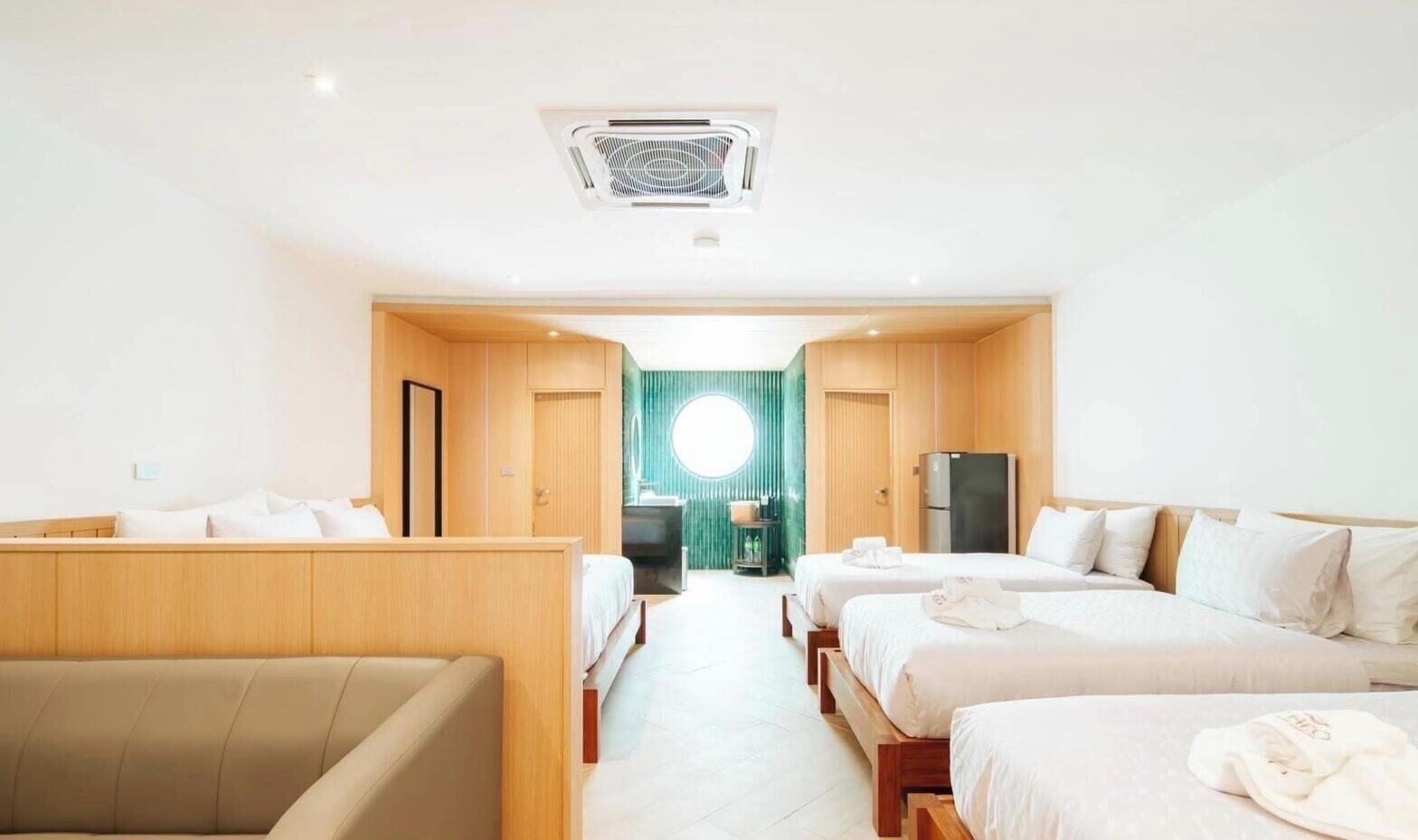 A hotel room with a bed, a sofa, a desk, and a view of a green outdoor area.