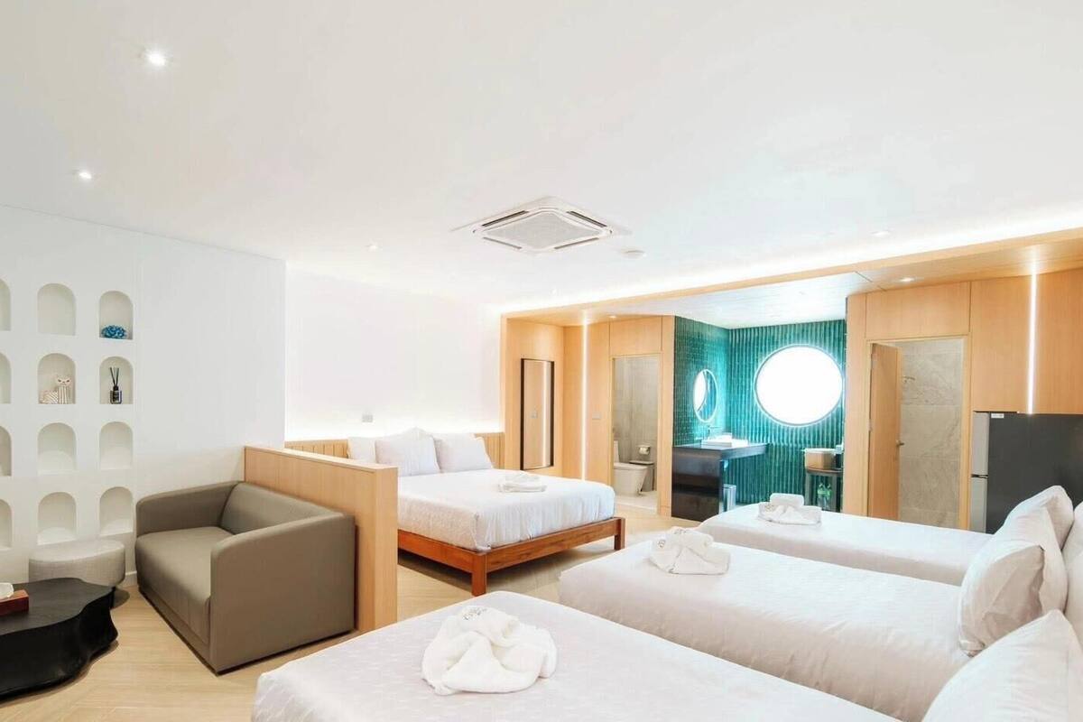 A hotel room with two beds, a sofa, a small table, and a wall with built-in shelves.