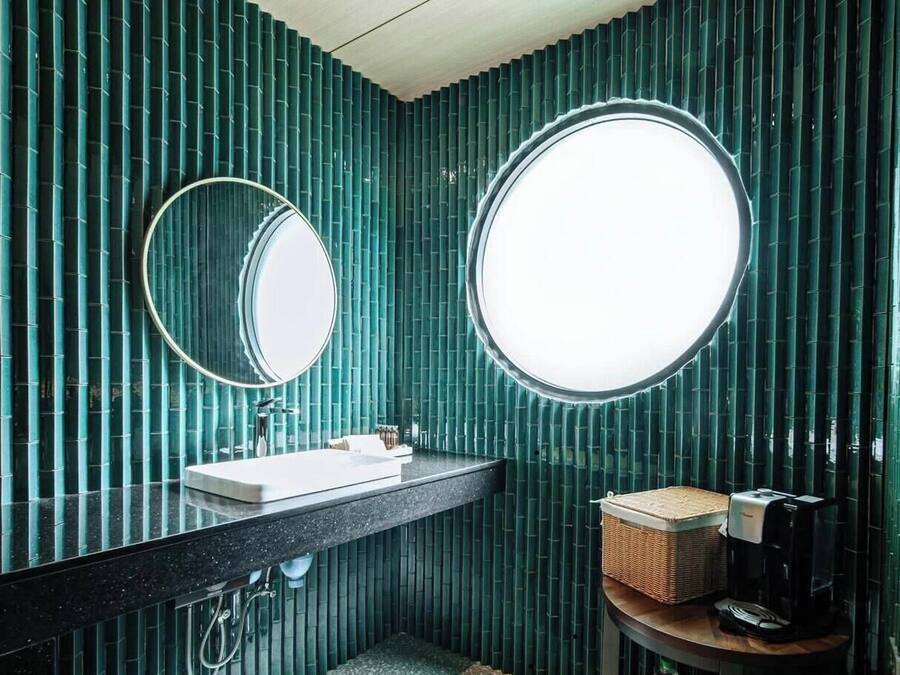 Un baño con un lavabo negro, dos espejos redondos y un ventanal circular.