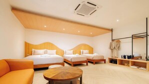 A hotel room with two beds, a sofa, a round table, and a mirror with clothes hanging. - Théo Privé Kohlarn (Koh Lan)