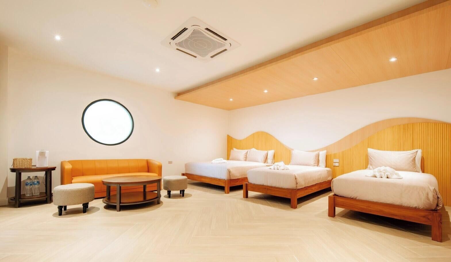A hotel room with a round table, two beds, a sofa, and a small table with bottles.