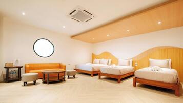 A hotel room with a round table, two beds, a sofa, and a small table with bottles.