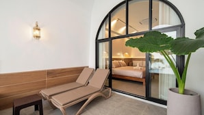 A sun lounger, a bench, and a large potted plant in a room with a large window. - Théo Privé Kohlarn (Koh Lan)