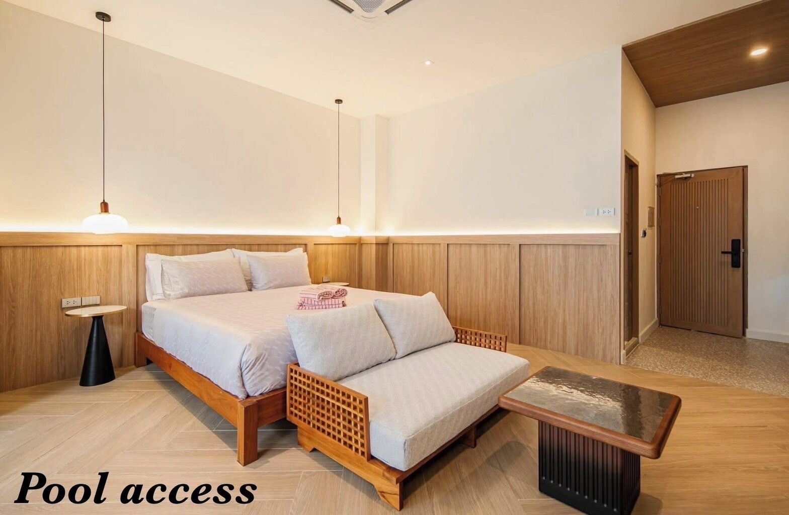 A bedroom with a bed, bedside table, and a small table with a lamp. There is a door labeled 'Pool access' indicating a pool nearby.