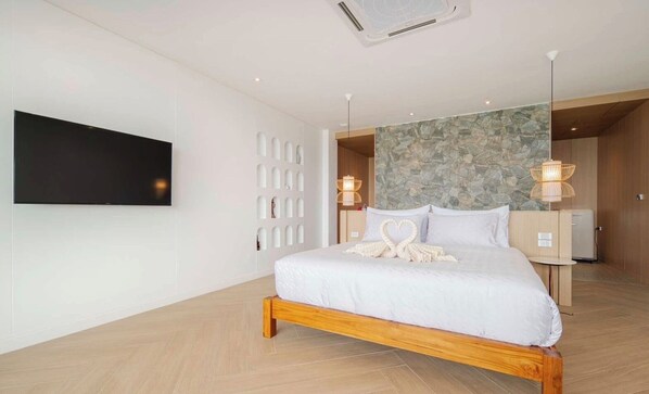 Ein modernes Hotelzimmer mit einem großen Bett, einem Flachbildfernseher, einer Wand mit Steinverkleidung und Holzboden.