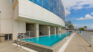 A modern building with a swimming pool, outdoor seating, and a view of the city skyline. - Island Tower 701 (Gulf Shores)