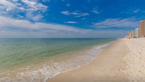 A beach with a clear sky and calm sea, featuring a sandy shore and high-rise buildings in the background. - Island Tower 701 (Gulf Shores)