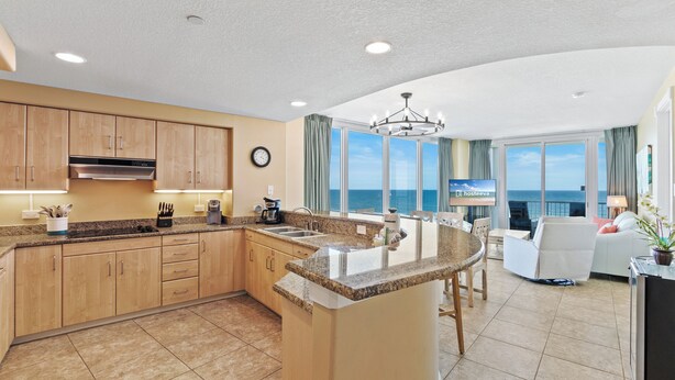A modern kitchen with granite countertops, wooden cabinets, and a central island. - Island Tower 701 (Gulf Shores)