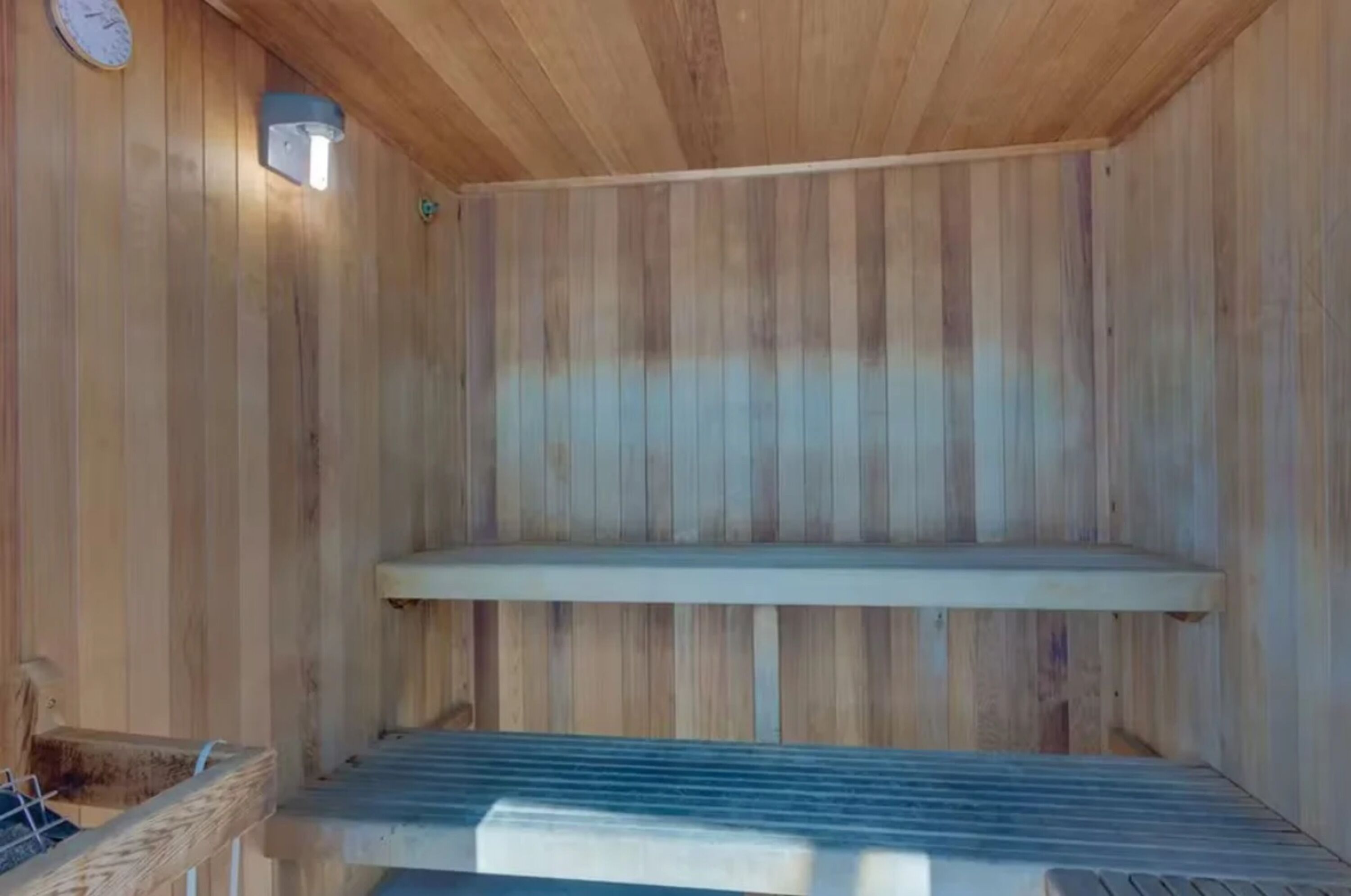 Una sauna in legno con una panca e un focolare a parete.
