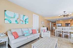 A living room with a sofa, coffee table, and artwork on the wall. - Island Tower 701 (Gulf Shores)