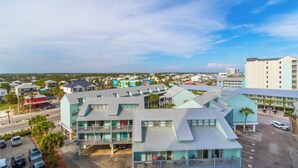 A multi-story hotel with a modern design, featuring balconies, a parking lot, and a view of the surrounding area. - Island Tower 701 (Gulf Shores)