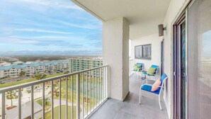 A balcony with a view of a tennis court, a building complex, and a clear sky. - Modern condo with Gulf view, shared pool - walk to the beach (Fort Morgan)