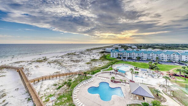 A resort with a beach view, a pool, and a building with multiple balconies. - Modern condo with Gulf view, shared pool - walk to the beach (Fort Morgan)