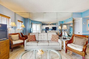 A living room with a sofa, two armchairs, a coffee table, and a television.