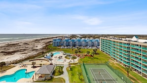 Ein Hotel mit Pool, Tennisplatz und Blick auf den Strand.