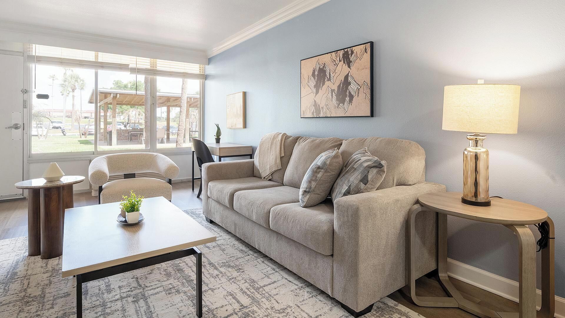 A living room with a sofa, a coffee table, a lamp, and a painting on the wall.