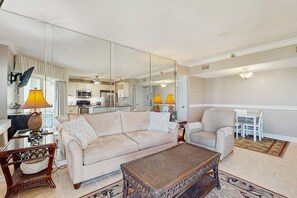 Ein Wohnzimmer mit einer Couch, einem Sessel, einem Couchtisch und einem Essbereich mit Tisch und Stühlen.