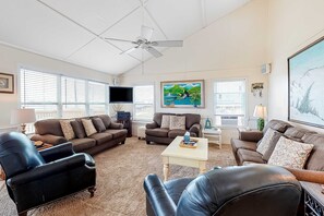A living room with a ceiling fan, two sofas, a coffee table, a TV, and artwork on the walls.
