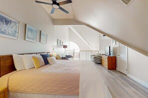Ein Schlafzimmer mit einem Bett, einem Schminktisch, einem Deckenventilator und einer Treppe zu einer oberen Ebene.