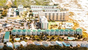 Ett hotell vid kusten med flera byggnader, en parkeringsplats och ett område med strand.