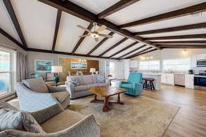 A spacious living area with a high ceiling, exposed beams, a wooden coffee table, and a kitchen with modern appliances. - Beachfront Home w/Spacious Deck, Gas Grill, Free WiFi, Incredible Views, A/C (Fort Morgan)
