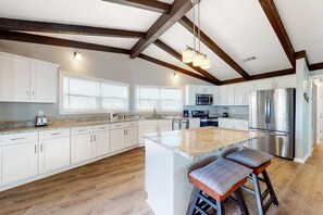A spacious kitchen with white cabinets, a large island, stainless steel appliances, and wooden beams on the ceiling. - Beachfront Home w/Spacious Deck, Gas Grill, Free WiFi, Incredible Views, A/C (Fort Morgan)