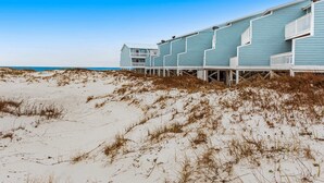 A beachfront hotel with multiple levels, wooden walkways, and a clear view of the ocean. - Recently Remodeled Condo w/Private Deck, Shared Outdoor Pool, Central AC, WiFi (Fort Morgan)