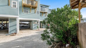 A two-story building with a covered outdoor area and a sandy ground. - Recently Remodeled Condo w/Private Deck, Shared Outdoor Pool, Central AC, WiFi (Fort Morgan)