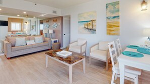 Een woonkamer met een bank, stoelen, een salontafel en kunst aan de wanden.