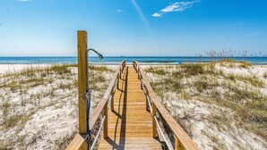 A wooden boardwalk leading to a beach with sand dunes and a clear blue sky. - Completely renovated oceanfront home with shared outdoor pool, views, & balcony (Fort Morgan)