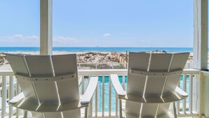 Two white chairs facing a pool with a beach view. - Completely renovated oceanfront home with shared outdoor pool, views, & balcony (Fort Morgan)