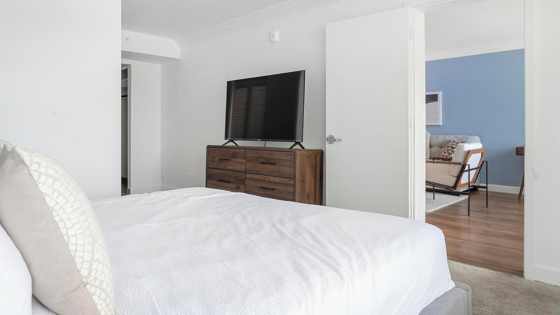 Quarto com cama, penteadeira e televisão.