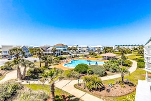 A resort with a swimming pool, palm trees, and a clear blue sky. - Bright corner condo steps from the beach with pools, hot tubs & tennis (Fort Morgan)