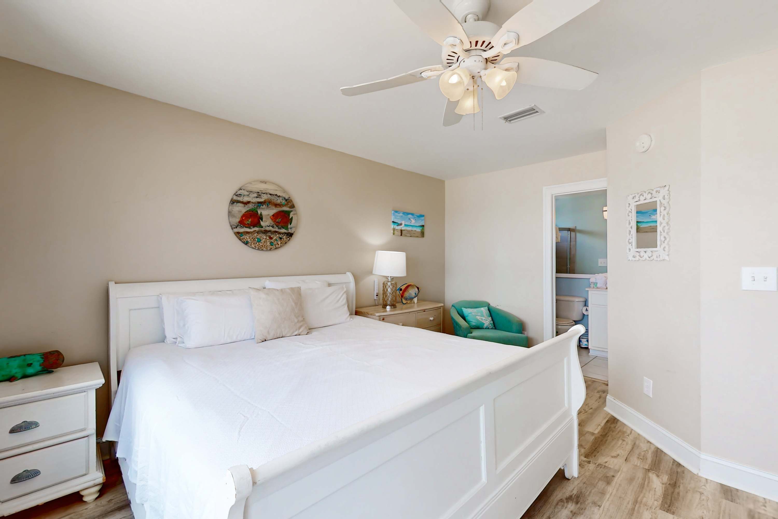 A bedroom with a bed, nightstand, lamp, and a ceiling fan.