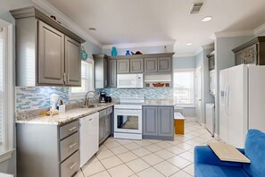 Een moderne keuken met grijze kastjes, een witte magnetron en een blauw aanrecht.