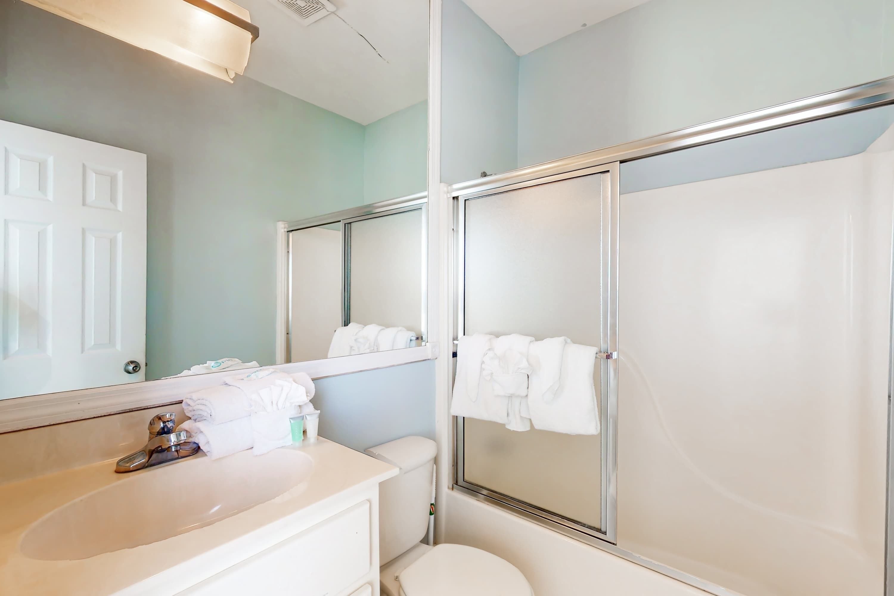 Een badkamer met een wastafel, spiegel, toilet en douchecabine.