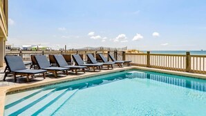 A pool with lounge chairs and a wooden fence overlooking the beach. - Luxury Beachfront Duplex in Fort Morgan | Pool, Elevator and Wedding-Friendly (Fort Morgan)