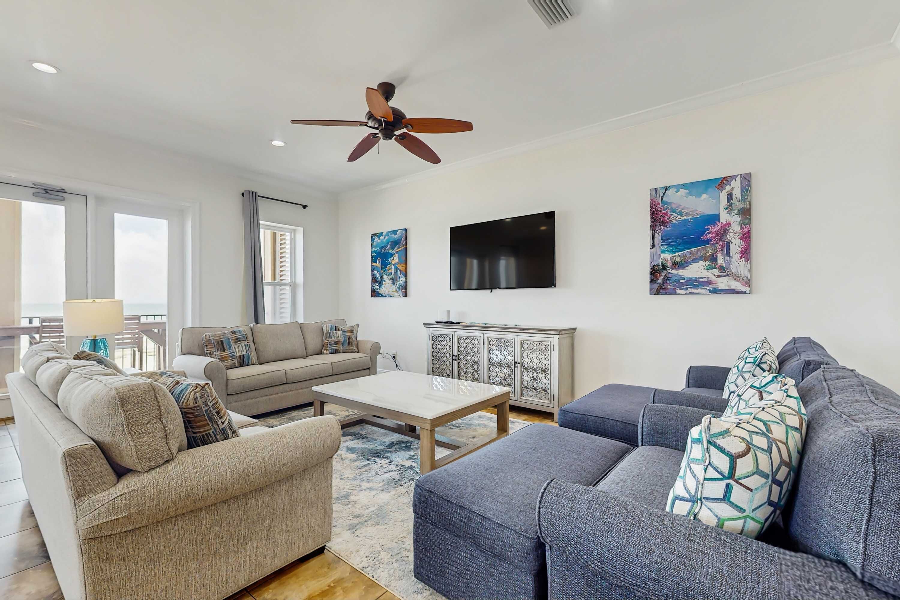 A living room with a sofa, armchairs, a coffee table, a TV, and artwork on the wall.
