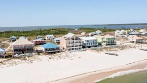 A coastal residential area with beachfront properties, including multi-story buildings with balconies, a sandy beach, and a view of the ocean. - Luxury Beachfront Duplex in Fort Morgan | Pool, Elevator and Wedding-Friendly (Fort Morgan)