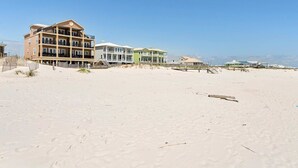 A beachfront hotel with multiple-story buildings, a sandy beach, and a clear sky. - Luxury Beachfront Duplex in Fort Morgan | Pool, Elevator and Wedding-Friendly (Fort Morgan)