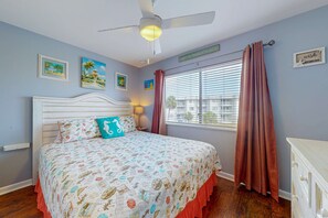 Un dormitorio con cama, ventilador de techo, ventana con cortinas y decoración en la pared.
