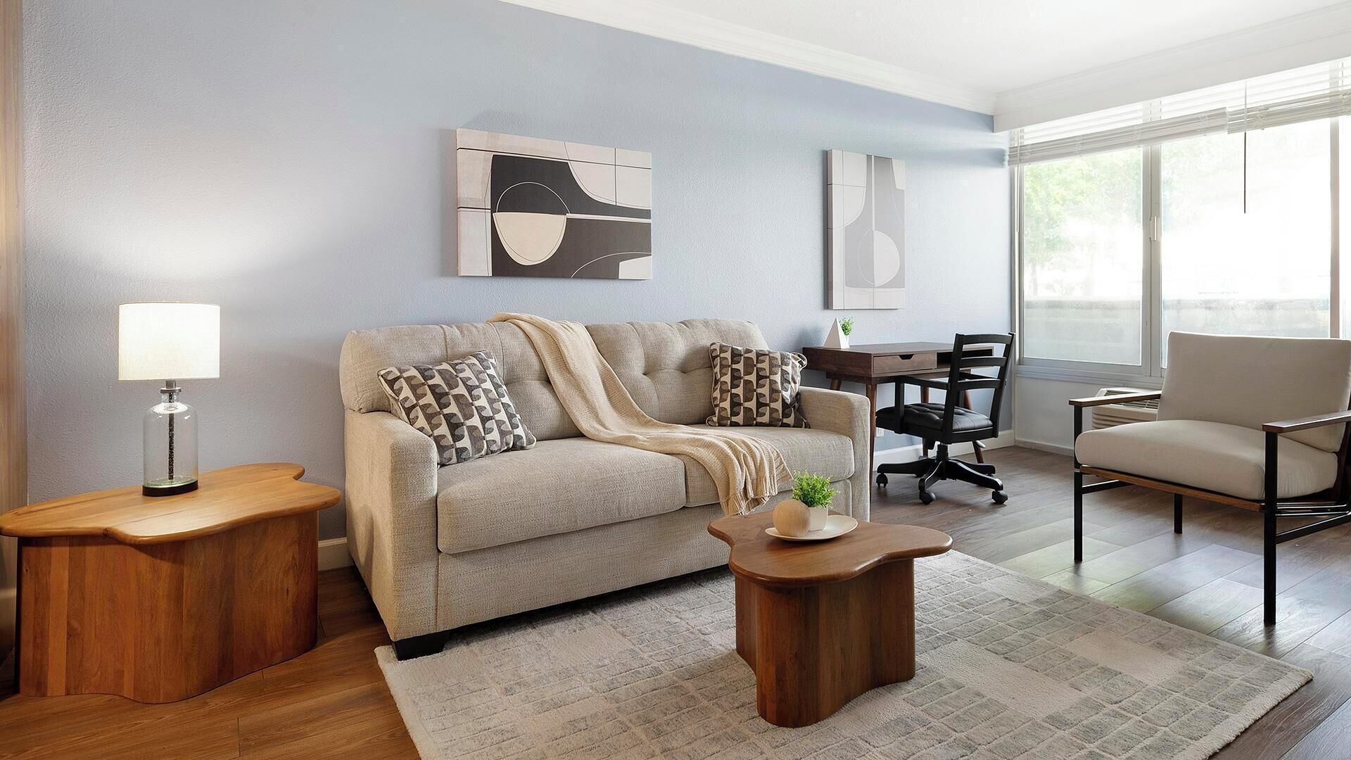 A modern living room with a sofa, coffee table, and a desk with a chair.