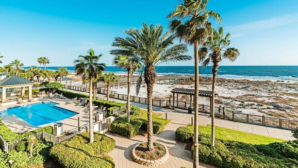 Un resort con piscina, palmeras y vista al mar.