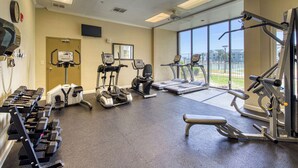 Ein Fitnessstudio mit Laufbändern, Crosstrainern, Krafttrainingsgeräten und Kurzhanteln.