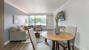 Uma sala de estar moderna com sofá, mesa de centro e mesa de jantar.