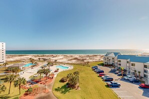A hotel with a pool, beach view, parking, and multiple buildings. - Gulf-front condo with balcony, shared pool, hot tub, & beach access (Fort Morgan)